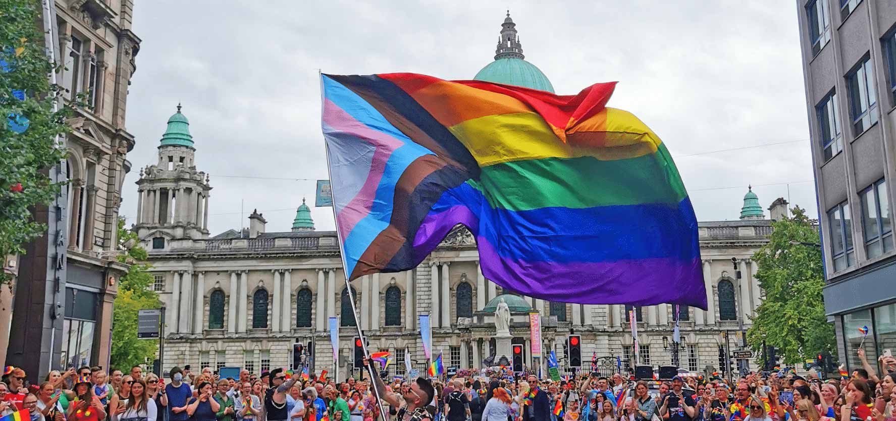 A member of the Rainbow Project waves a progress pride flag in front of City Hall during Belfast Pride. Picture: Rainbow Project