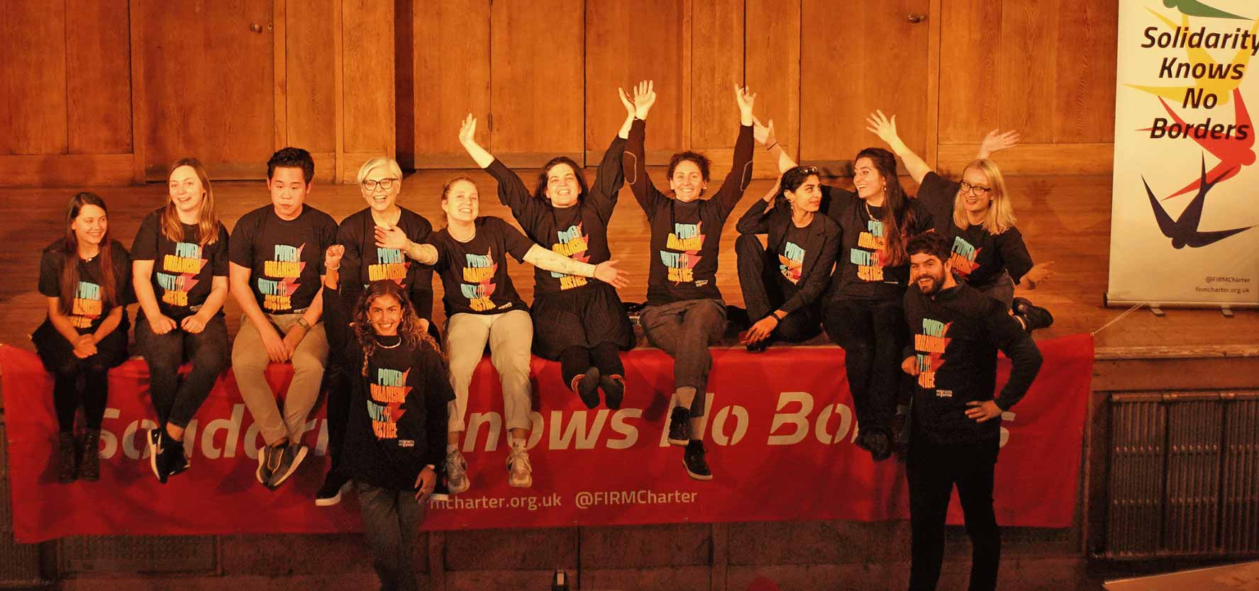 Twelve members of the Migrants Organise team are pictured on a stage with a banner reading 'solidarity knows no borders'. Picture: Migrants Organise